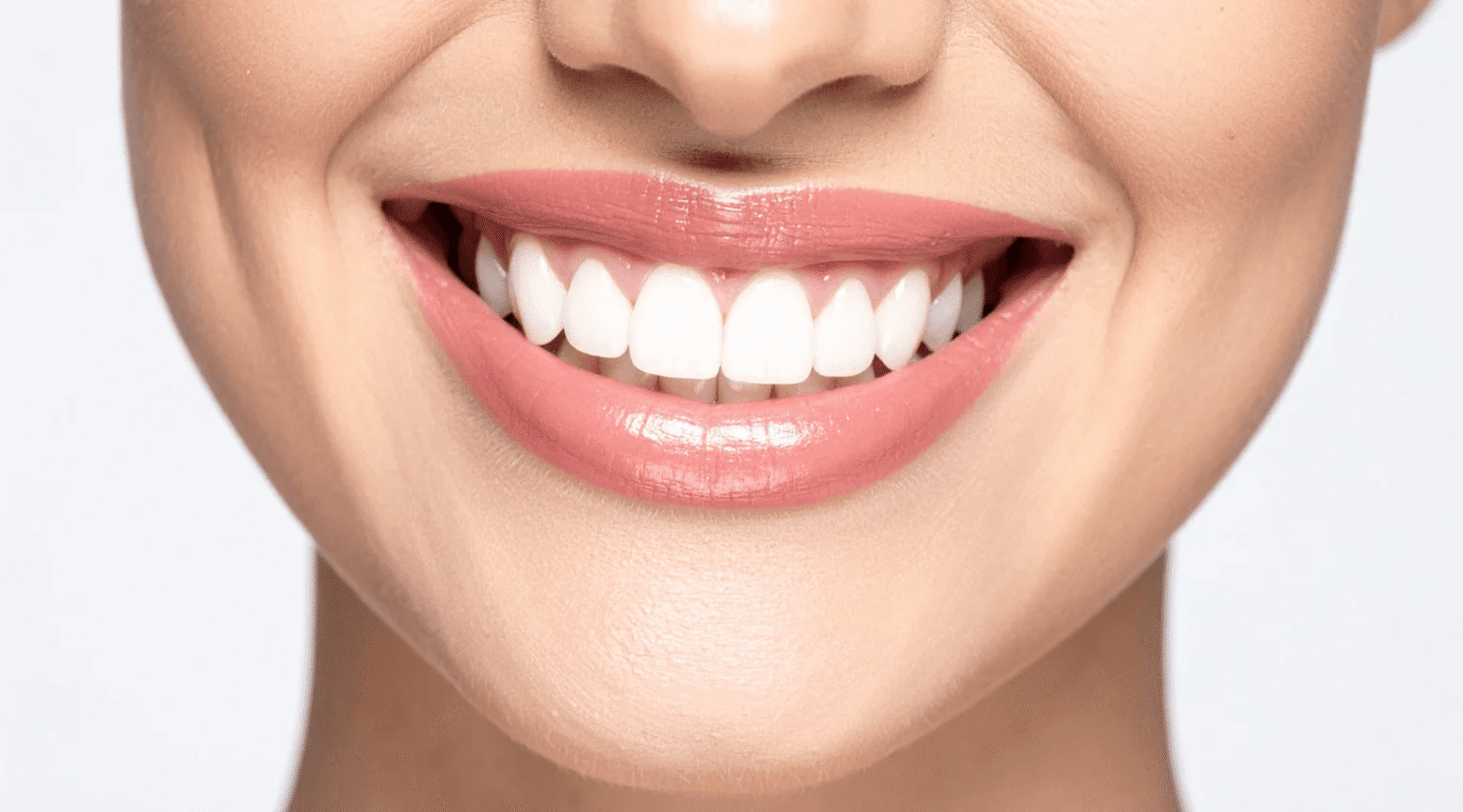 Close-up of a person smiling and showing white teeth.